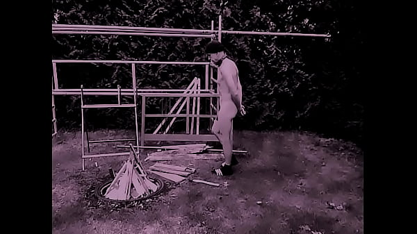 nagi nieobcięty, zdemaskowany niewolnik obnażony przygotowuje ognisko na gejowską imprezę na świeżym powietrzu głupi pedał rozłupuje drewno